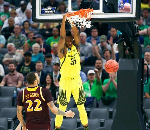 (AP Photo/Steve Yeater). Oregon forward Kavell Bigby-Williams hangs on the rim after dunking as Iona forward Taylor Bessick, left, looks on during the first half of a first-round game in the men's NCAA college basketball tournament in Sacramento.